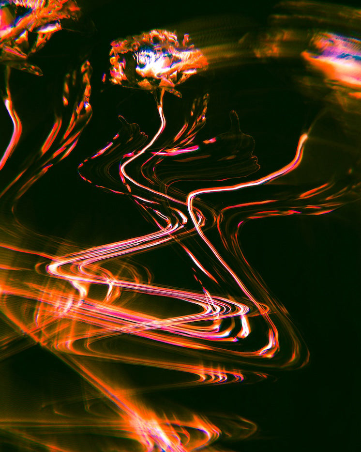 Abstract light painted holographic flowers with swirling patterns of orange, red and pink on a dark background